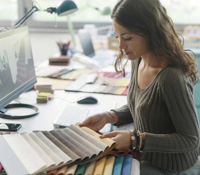 Professional decorator working in her studio, she is choosing fabric swatches for her project